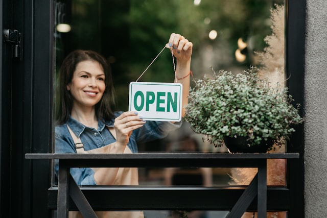 Photo of woman hanging "Open" sign in store window